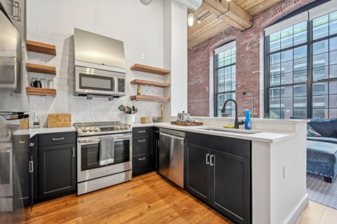 a kitchen with black and white cabinets and a large window at Riverwalk Apartments, Lawrence, MA